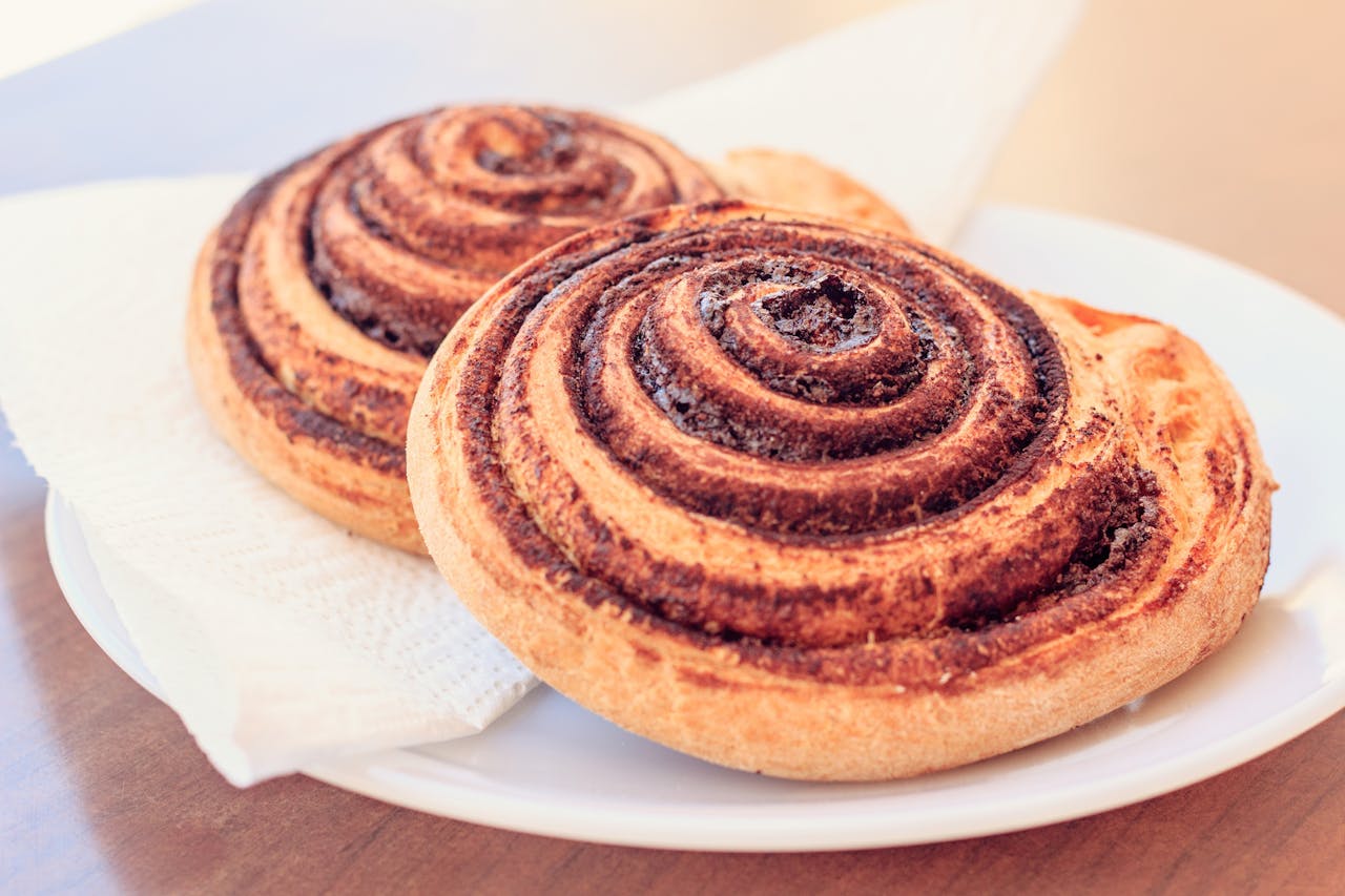 A close-up view of two freshly baked cinnamon rolls served on a white plate.
